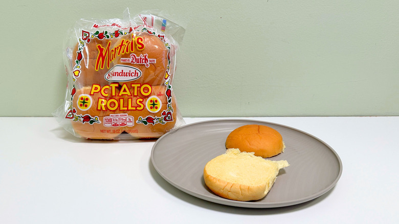 A bag of Martin's Potato Rolls next to a plate of hamburger buns
