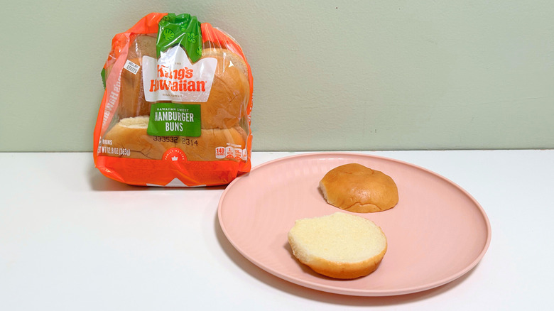 A bag of King's Hawaiian Hawaiian Sweet Hamburger Buns next to a plate of hamburger buns