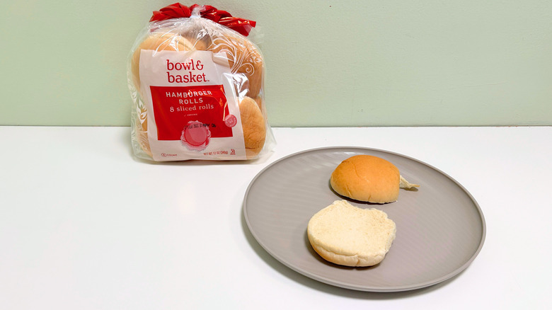 A bag of Bowl and Basket Hamburger Rolls next to a plate of hamburger buns