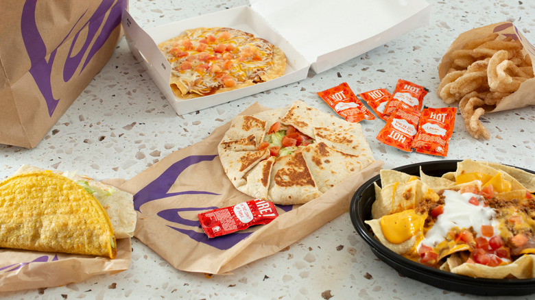 Various Taco Bell menu items like tacos, Crunchwrap, and Cinnamon Twists laid out on a table