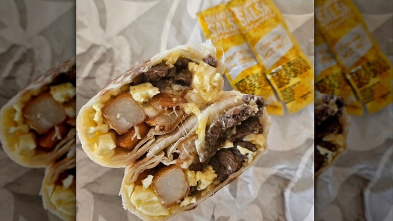Cross section of a Taco Bell Steak Burrito with salsa packets on the side