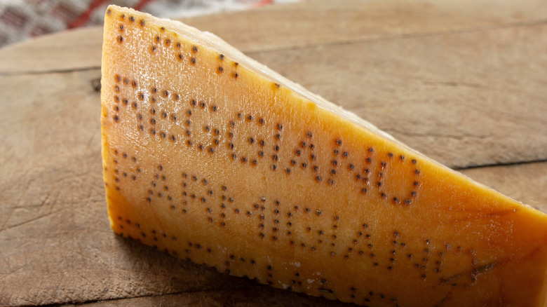 A closeup on the rind of a Parmigiano Reggiano wedge on a wooden table