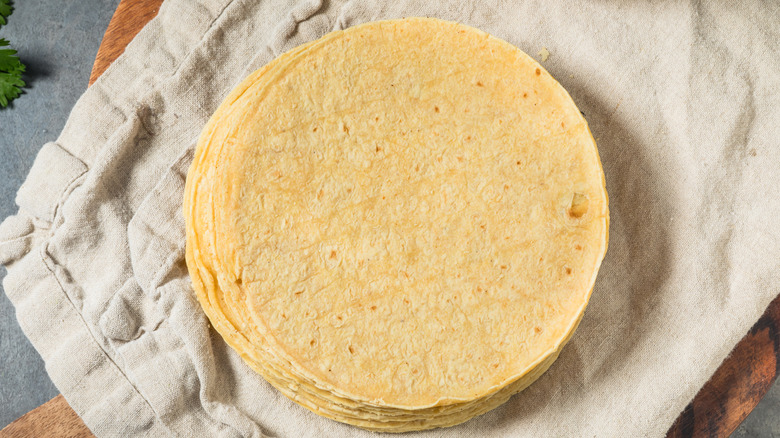 A pile of corn tortillas on a beige cloth