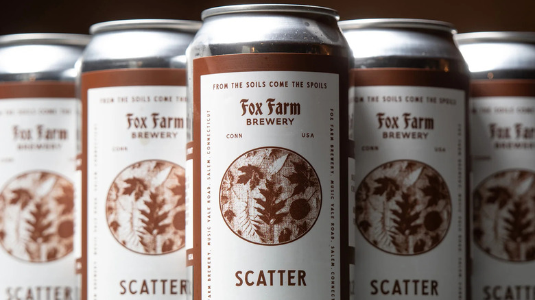 cans of scatter brown ale on black background