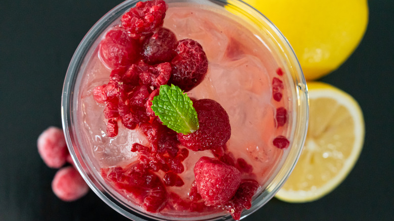 Overhead view of a glass of raspberry lemonade topped with extra raspberries