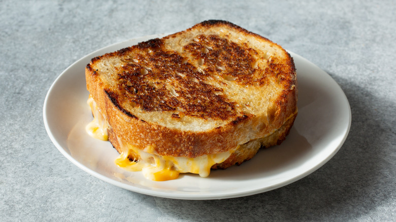 A grilled cheese sandwich on a plate placed on a marble table