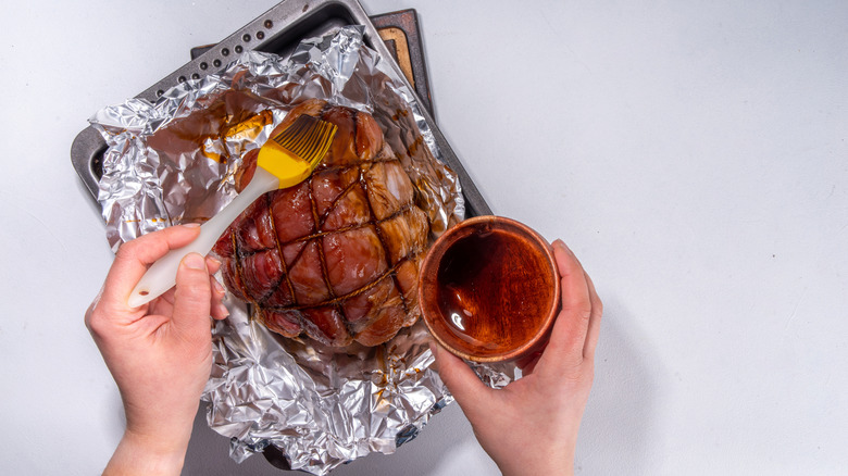 A person brushing meat with a simple glaze