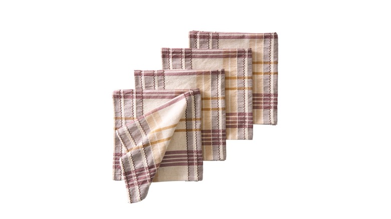Four plaid linen napkins in a neutral color palette against a white background.