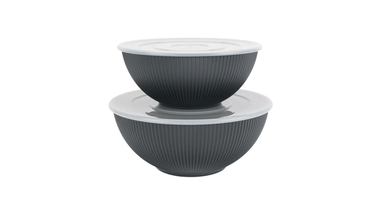 Two ribbed black bowls with lids stacked on each other against a white background.