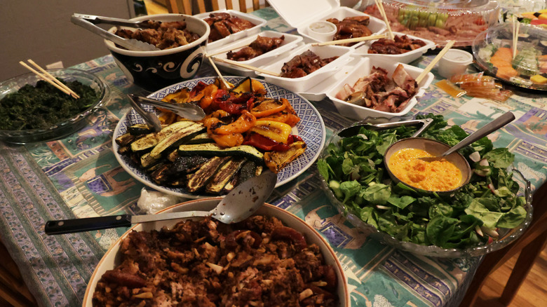 A table covered with serving plates and bowls of potluck food
