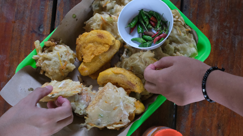 Two people's hands reaching for food on the same plate without using utensils