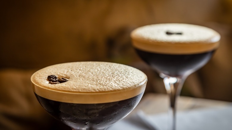 A close up of two espresso martinis on a bar with coffee bean garnishes