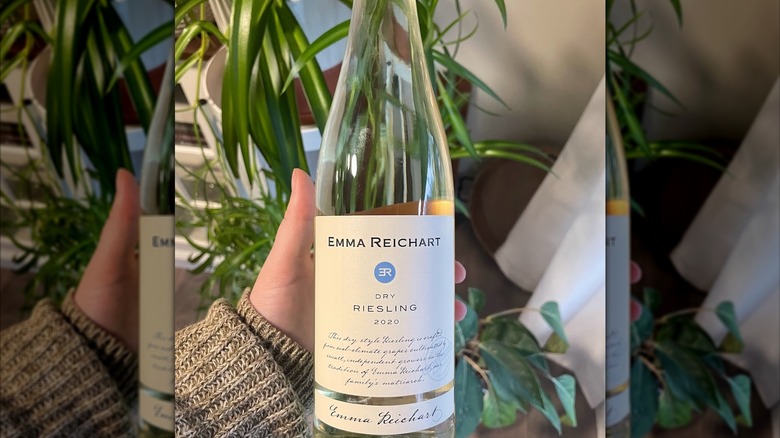 A hand holding a bottle of Emma Reichart dry riesling wine.