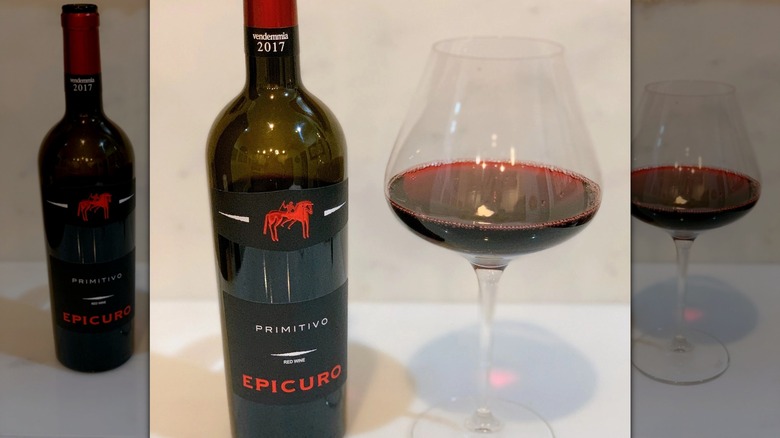 Epicuro wine with a red, white and black label and a glass with red wine next to it.