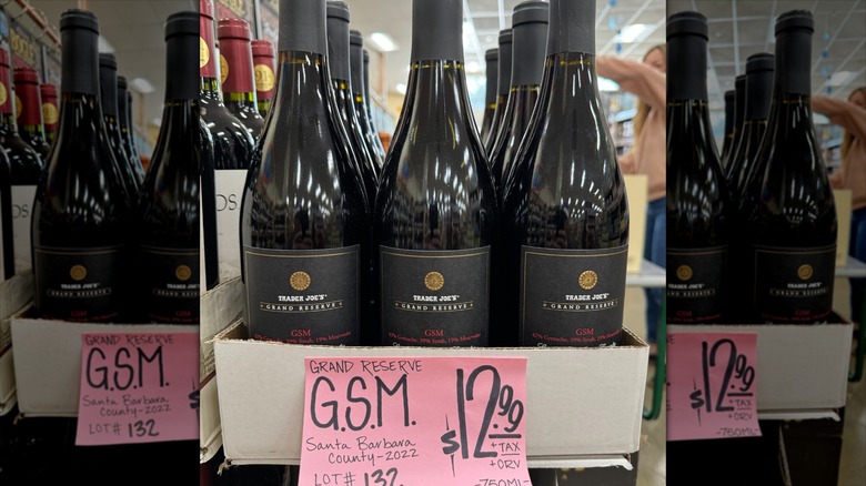 A case of Trader Joe's Grand Reserve wine with a black label and a pink sign advertising them.