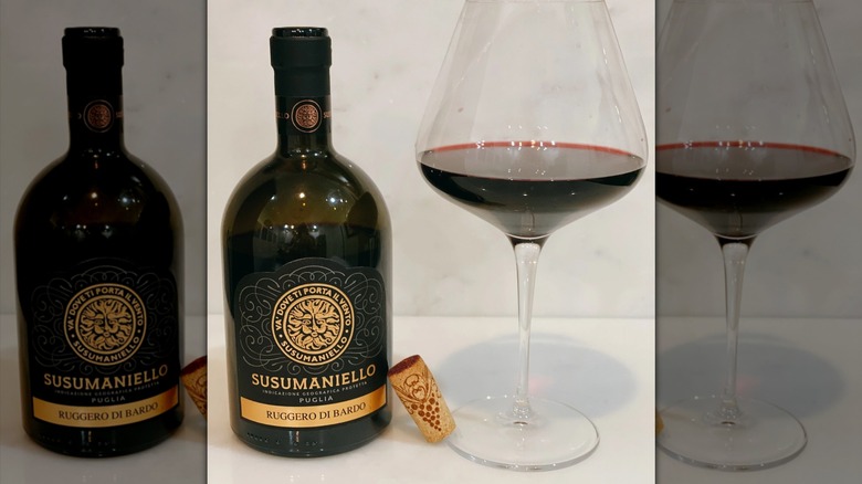 Ruggero di Bardo wine with a black and gold label in a stout bottle with a glass of red wine next to it.