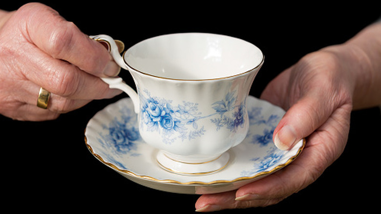 Hands holding tea cup and saucer