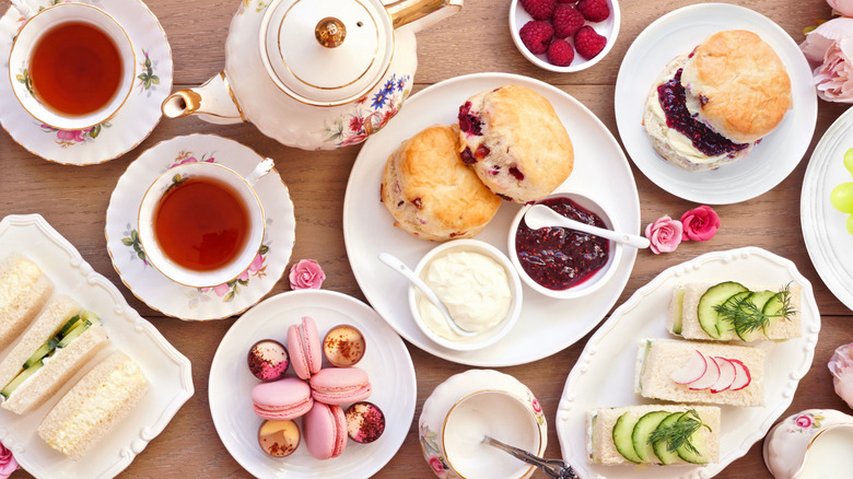 Overhead shot of tea and plates of sandwiches and scones