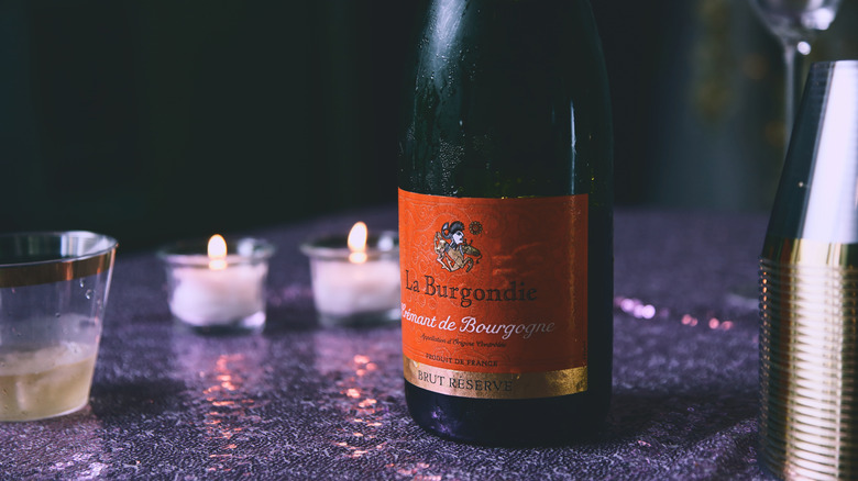 A bottle of La Burgondie sparkling wine on a table with candles.
