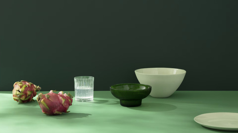 A deep green wall with a lighter green surface below, littered with bowls and plates