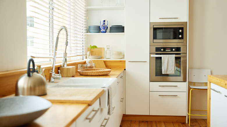 A modern kitchen with bright white cabinets and walls in a darker shade of white