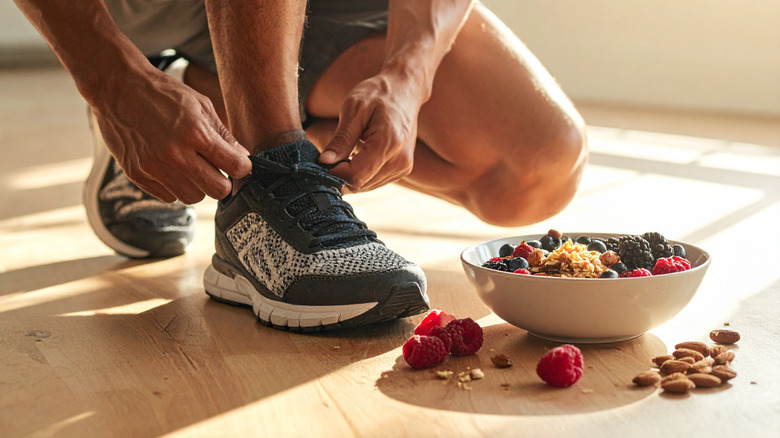 Bowl of fruit and nuts next to man lacing up shoes