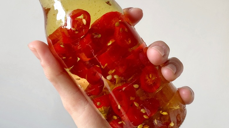 A hand holding a jar of chile-infused syrup