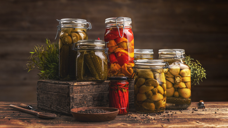 Several jars of various pickled vegetables on a wooden table