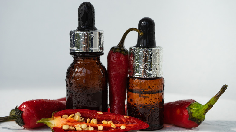 Two small dropper bottles and several whole and sliced chiles