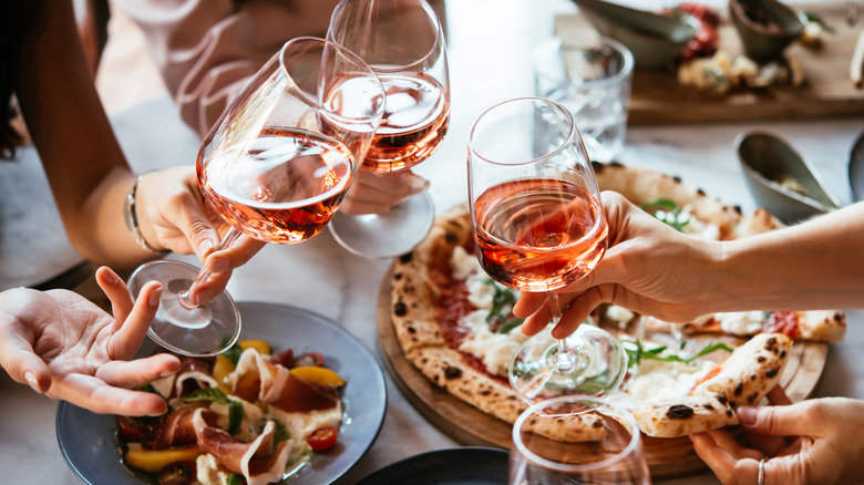 Friends cheers with wine over a spread of Italian food at a restaurant