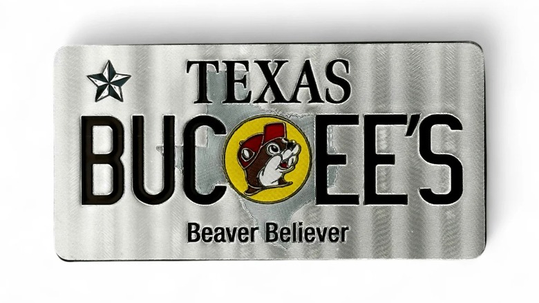 A silvery fridge magnet resembling a Texas license plate that says "Buc-ee's" against a white background