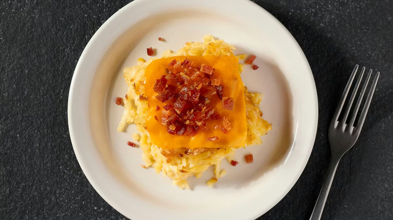An overhead photo of a white plate with Cracker Barrel's Loaded Hashbrown Casserole against a black table
