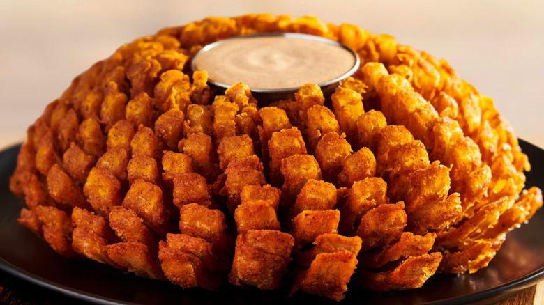 A large fried onion from Outback Steakhouse with dipping sauce in the middle