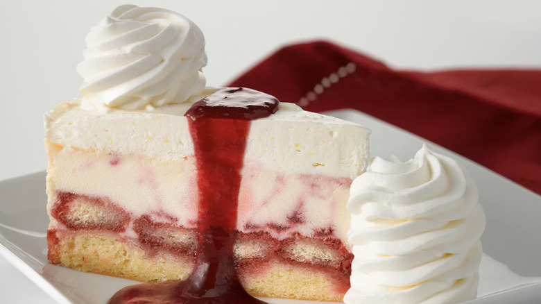 Lemon Raspberry Cream Cheesecake from The Cheesecake Factory on a white plate topped with raspberry puree and whipped cream