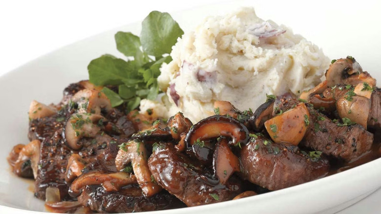 A plate of Steak Diane from The Cheesecake Factory on a white table