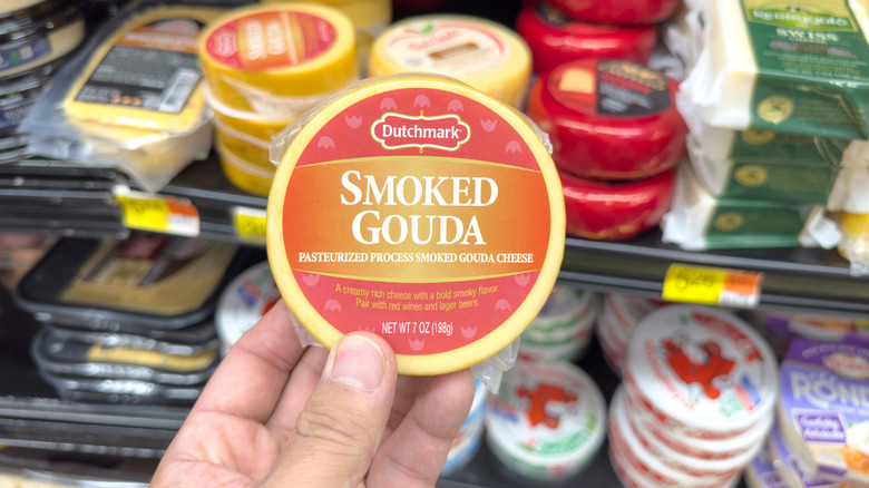 Hand holding wheel of smoked Gouda