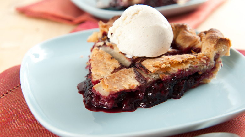 A piece of marionberry pie with a scoop of vanilla ice cream