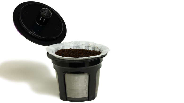 Disposable coffee pod with coffee grounds inside, lid off
