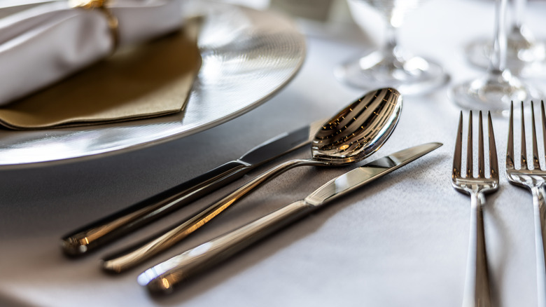 A close-up of nice silverware on a white tablecloth at a restaurant