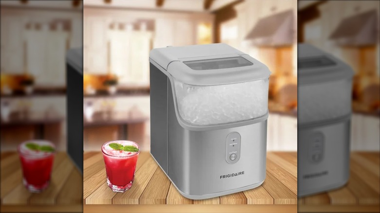 A gray Frigidaire countertop ice maker next to a red drink with ice