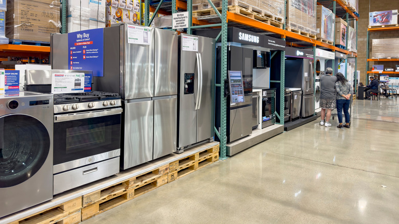 Many appliances inside a Costco, two people in the background.
