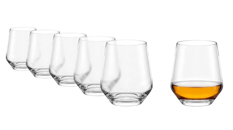 Five empty Costco whiskey glasses next to one with whiskey in it