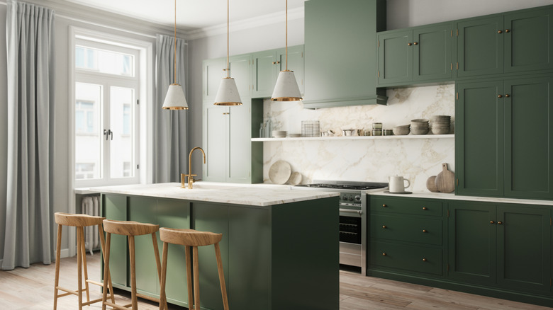 A kitchen with forest green cabinets and white countertops and light wooden counter stools