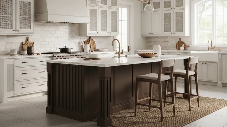 Kitchen island with marble top and brown-painted base in a white kitchen