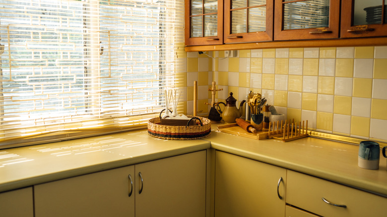 A vintage kitchen with mustard yellow cabinets, countertops, and tiles