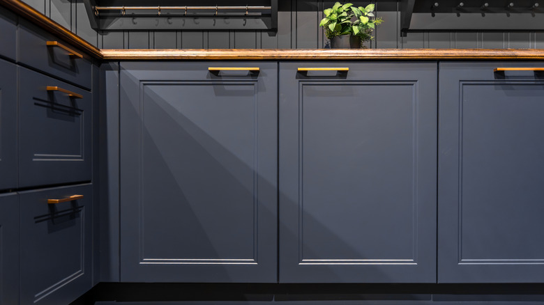 Navy blue kitchen cabinets with gold hardware and brown wood countertops