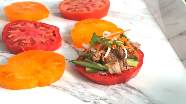 Vietnamese banh mi tomato on a marble-like background with other tomato slices