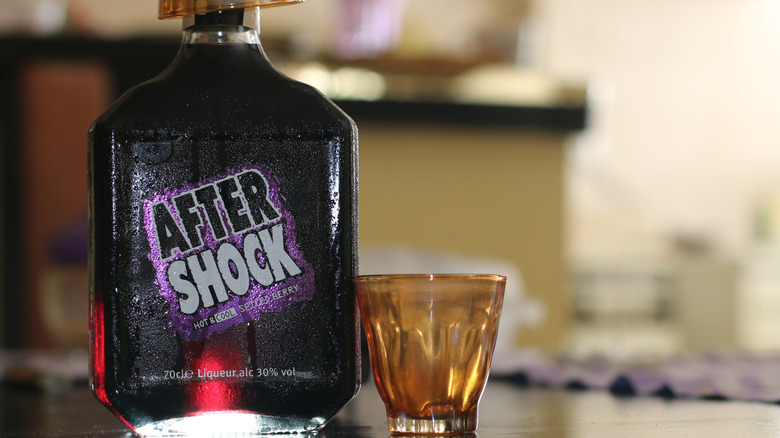 A bottle of Aftershock Spiced Berry sits next to a shot glass