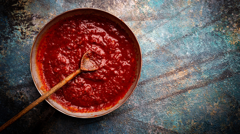 A bowl filled with homemade tomato sauce on a multicolored background