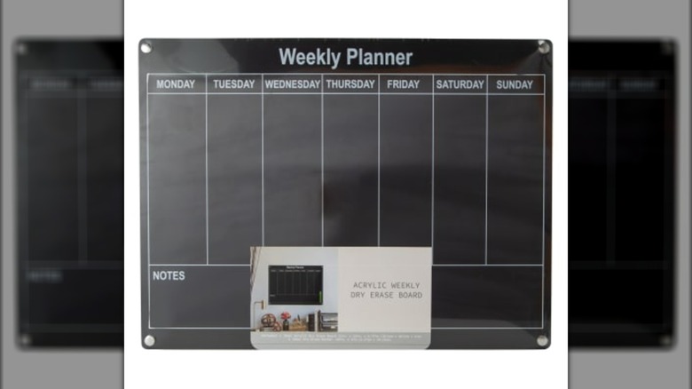 A black dry erase board with a Monday-Sunday weekly planner on it